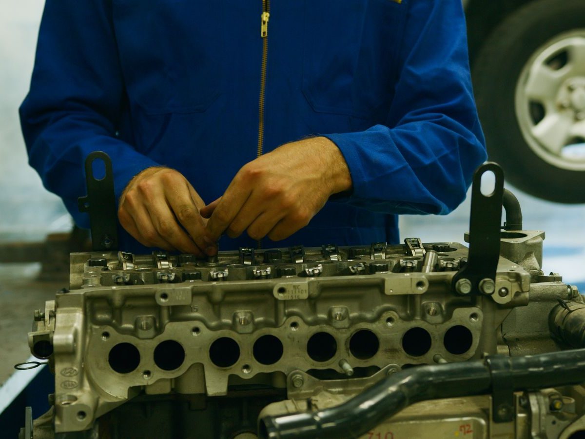 Hände eines Mechanikers arbeiten an einem Zylinderkopf